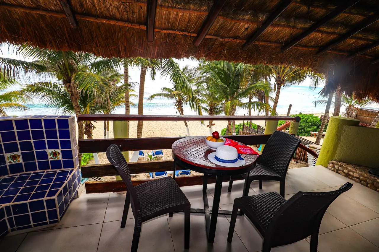 Furnished veranda with a table for two overlooking palm trees and the beach